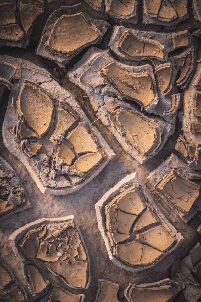 Fotografía aérea de estructuras minerales fracturadas con patrones geométricos y tonos ocres y terrosos.