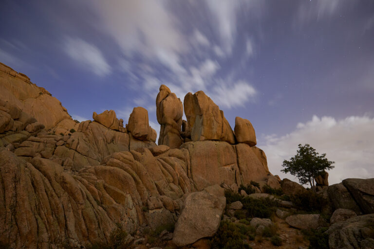 Formaciones rocosas graníticas con acumulación de grandes bloques de piedra bajo cielo azul y nubes dispersas