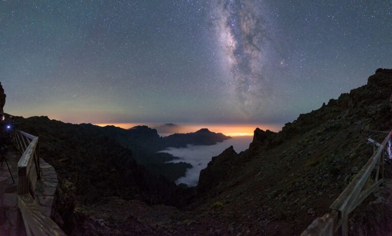 Vía Láctea sobre valle montañoso con mar de nubes al atardecer en La Palma, Islas Canarias