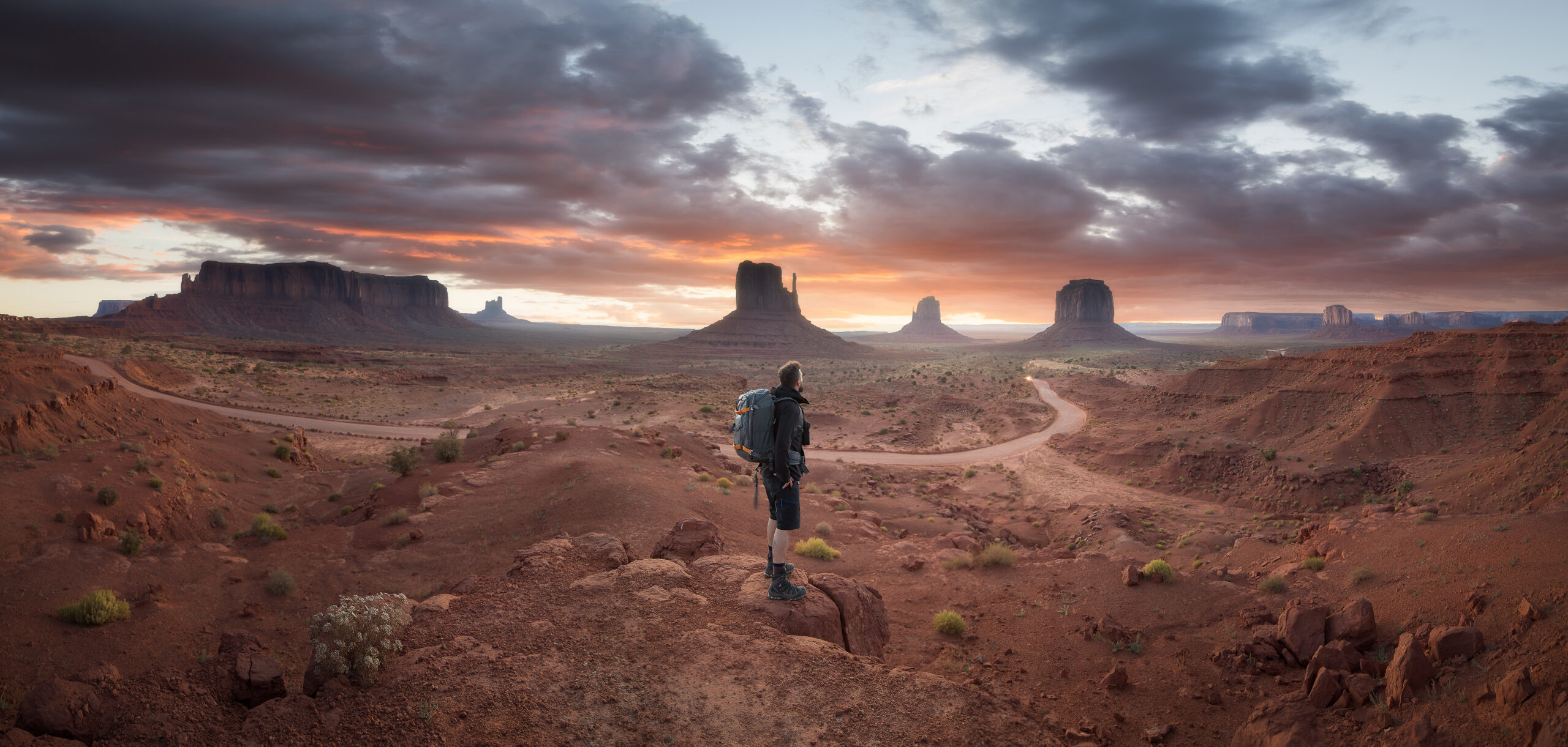 Senderista con mochila observa los monumentos de Monument Valley al atardecer