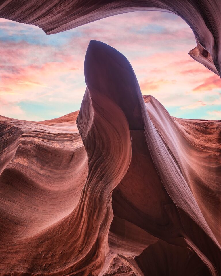 Cañón de arenisca roja con formaciones rocosas ondulantes y cielo rosa al atardecer