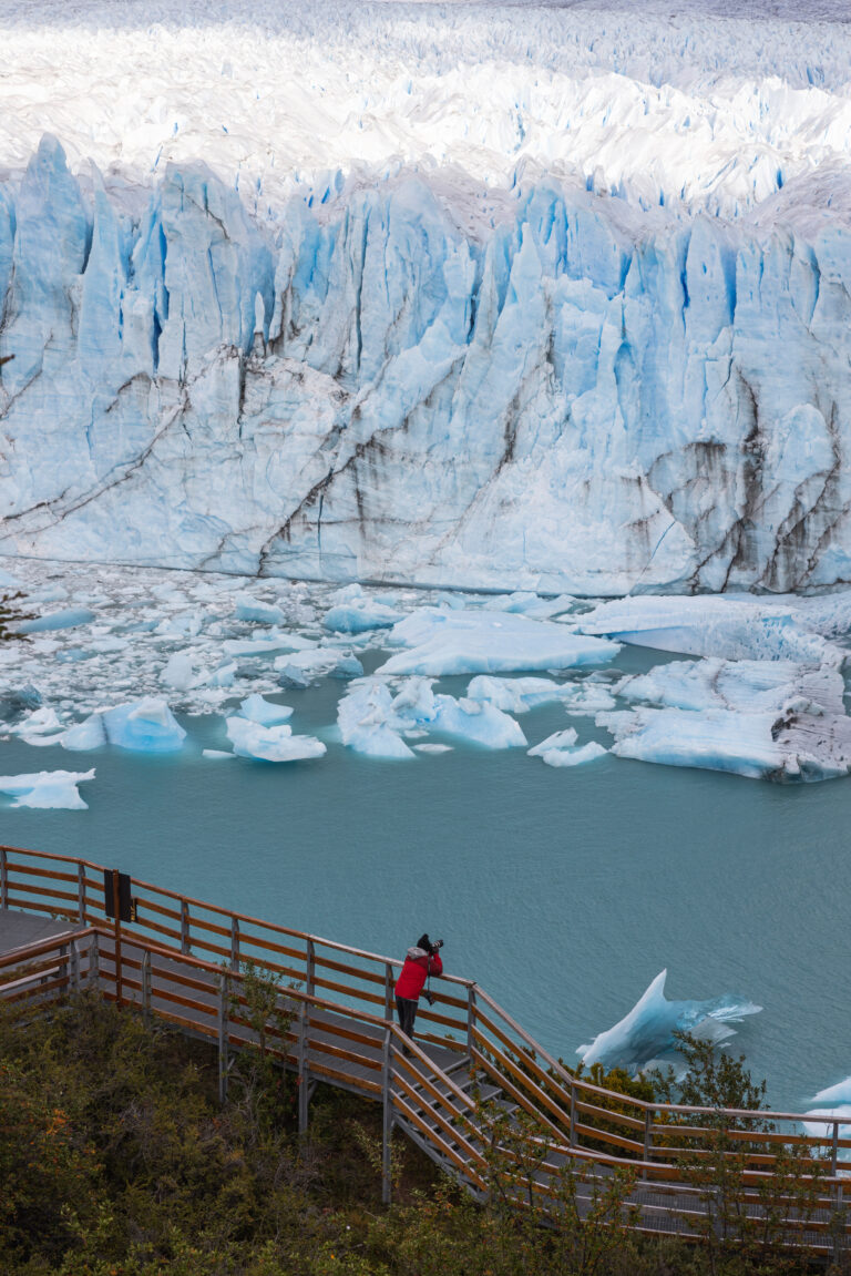 Viajero en mirador observa el glaciar Perito Moreno con icebergs flotantes en el lago glaciar de Patagonia