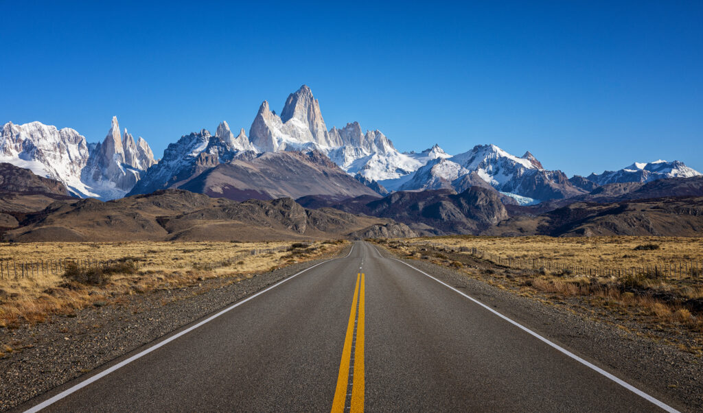 Ruta recta hacia el Monte Fitz Roy con picos nevados al fondo en la Patagonia argentina