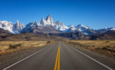 Ruta recta hacia el Monte Fitz Roy con picos nevados al fondo en la Patagonia argentina