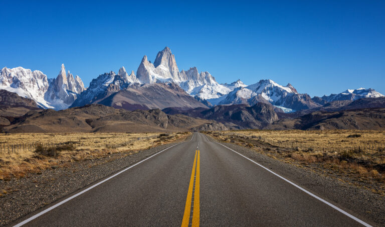 Ruta recta hacia el Monte Fitz Roy con picos nevados al fondo en la Patagonia argentina