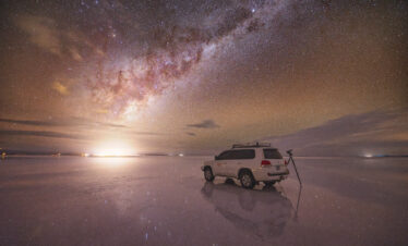 Vehículo 4x4 en el Salar de Uyuni bajo la Vía Láctea al atardecer