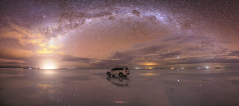 Vehículo 4x4 en el Salar de Uyuni bajo la Vía Láctea y cielo estrellado al atardecer
