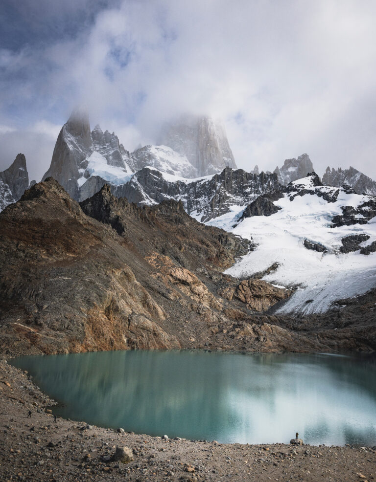 Lago glaciar turquesa al pie de montañas nevadas y picos rocosos en la Patagonia