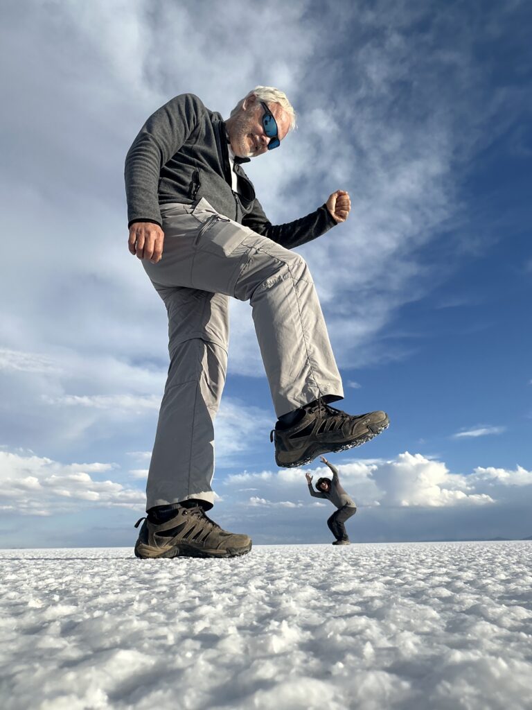 Hombre saltando en el Salar de Uyuni con cielo nublado de fondo y perspectiva forzada