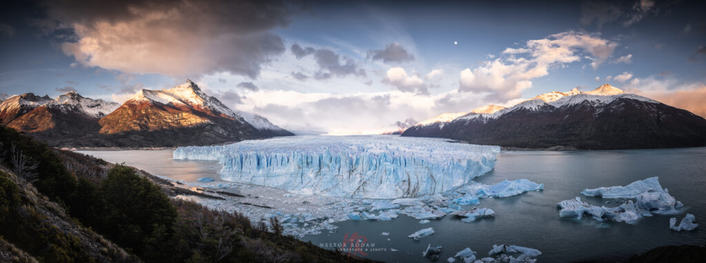Glaciar Perito Moreno con iceberg azul flotante rodeado de montañas nevadas y lago en Patagonia