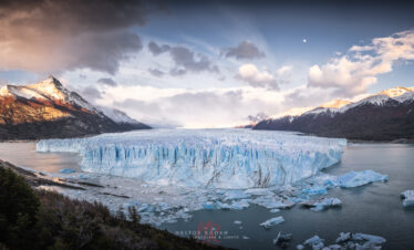 Glaciar Perito Moreno con iceberg azul flotante rodeado de montañas nevadas y lago en Patagonia