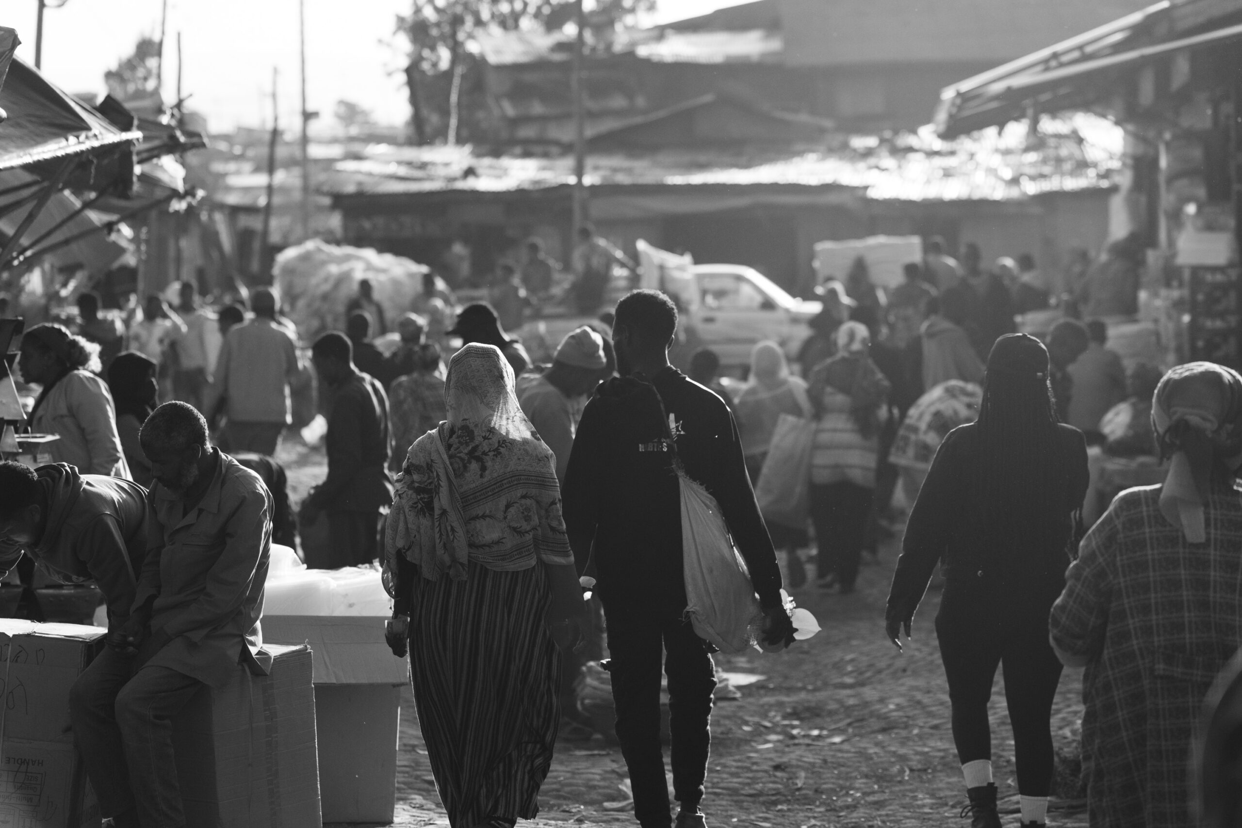 Mercado tradicional etíope lleno de gente caminando entre puestos y tiendas al atardecer