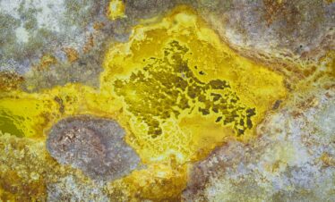 Depósitos minerales amarillos y grises en formaciones geotérmicas con texturas cristalizadas