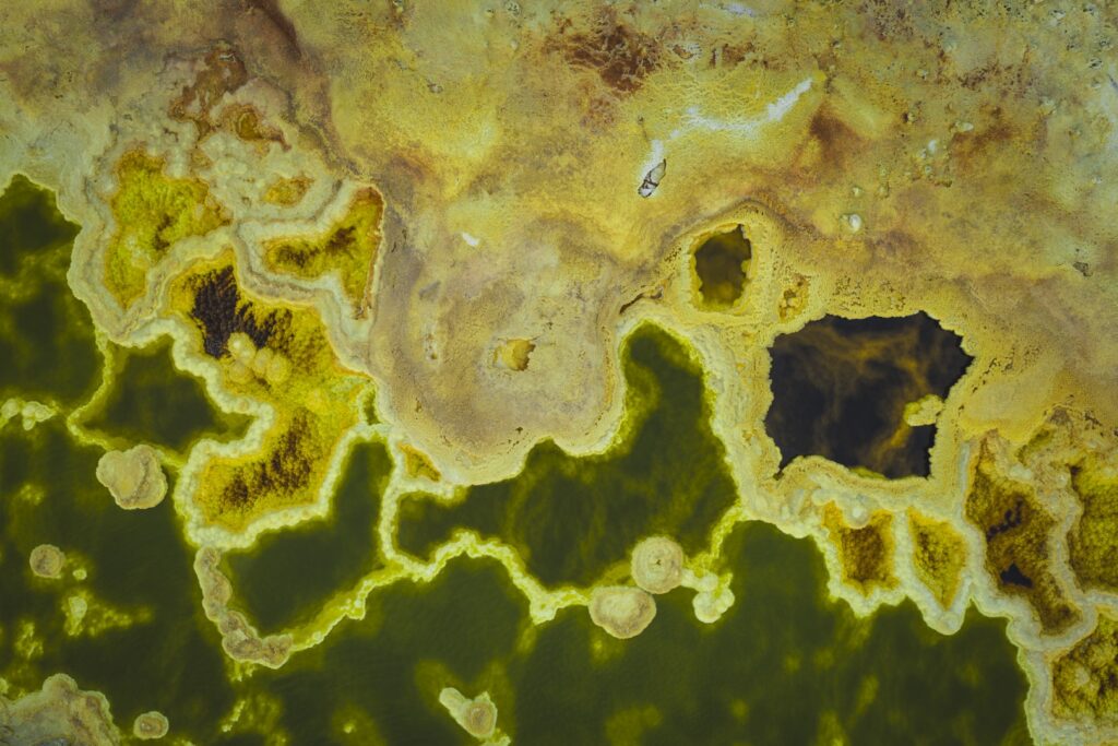 Vista aérea de géiseres y piscinas termales con agua verde y bordes minerales amarillos en Etiopía