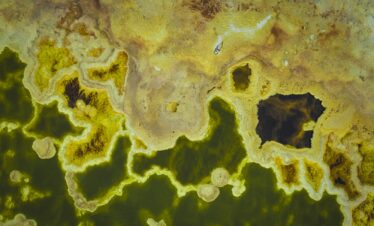 Vista aérea de géiseres y piscinas termales con agua verde y bordes minerales amarillos en Etiopía