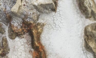 Detalle de depósitos minerales blancos y formaciones geológicas con coloración ocre en terreno árido