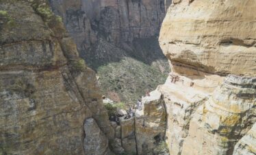 Garganta de roca con sendero entre acantilados de piedra arenisca y senderistas explorando el cañón