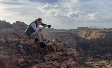 Fotógrafo con teleobjetivo en acantilado rocoso capturando el paisaje de cañones y valles de Etiopía