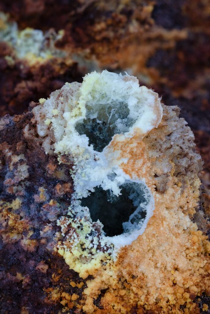 Roca volcánica con cristales minerales blancos y depósitos de azufre amarillo en Etiopía