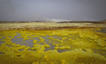 Aguas termales amarillentas con depósitos minerales en paisaje volcánico de Etiopía