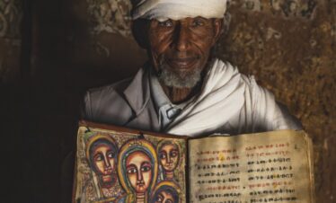 Sacerdote etíope sosteniendo un antiguo manuscrito iluminado con iconografía religiosa tradicional