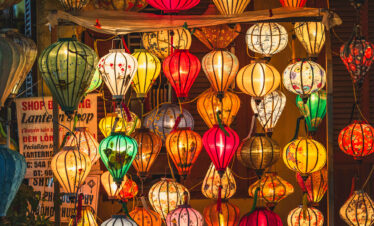 Tienda de linternas tradicionales vietnamitas de colores vibrantes colgadas en la entrada, rojo, amarillo, blanco y verde en Hoi An