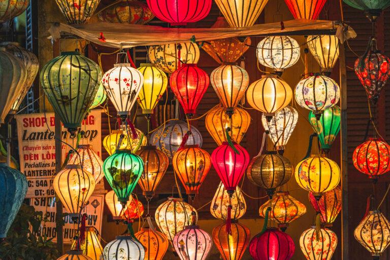 Tienda de linternas tradicionales vietnamitas de colores vibrantes colgadas en la entrada, rojo, amarillo, blanco y verde en Hoi An