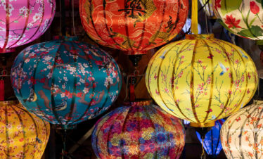 Linternas tradicionales vietnamitas de colores vibrantes colgadas en un mercado, con diseños florales y patrones asiáticos