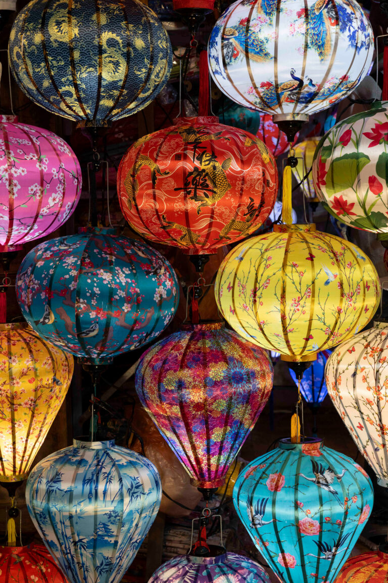 Linternas tradicionales vietnamitas de colores vibrantes colgadas en un mercado, con diseños florales y patrones asiáticos