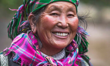 Mujer sonriente con tocado y bufanda tradicionales de colores vibrantes en Vietnam