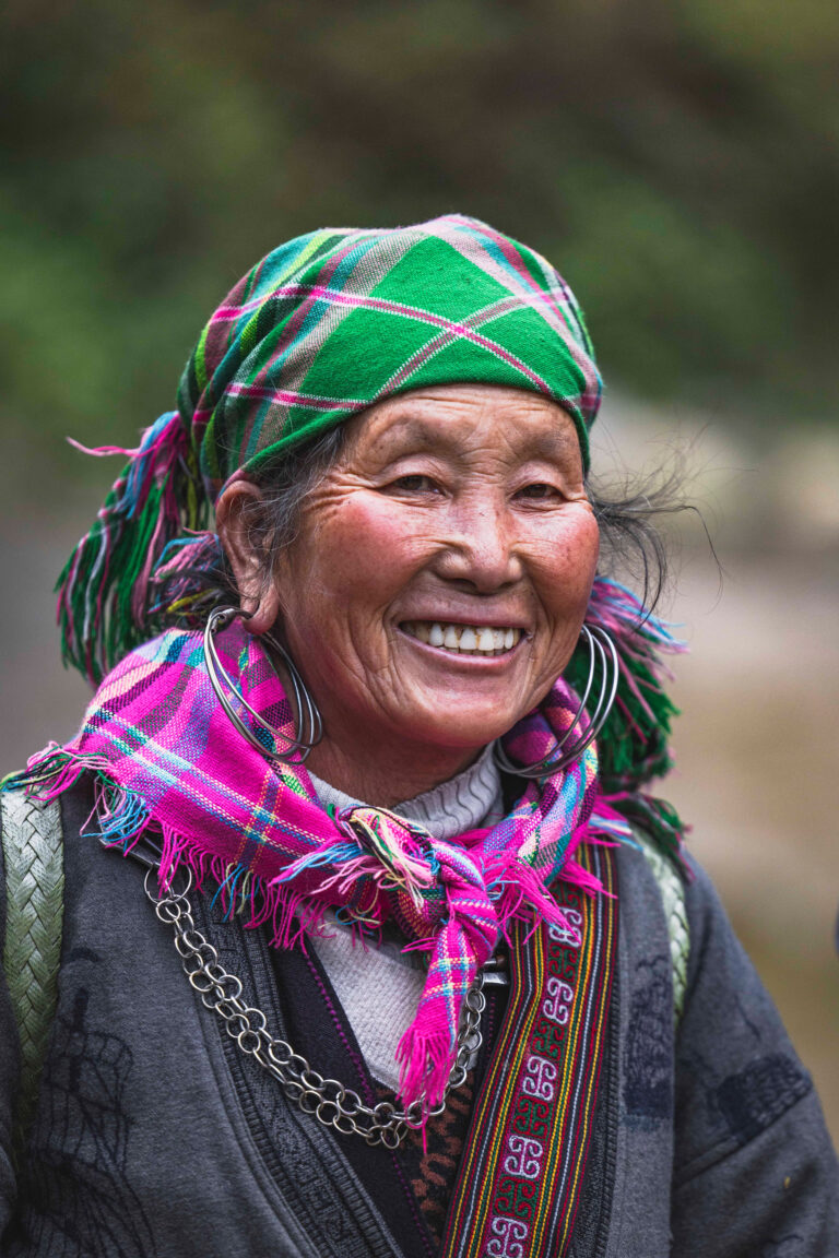 Mujer sonriente con tocado y bufanda tradicionales de colores vibrantes en Vietnam