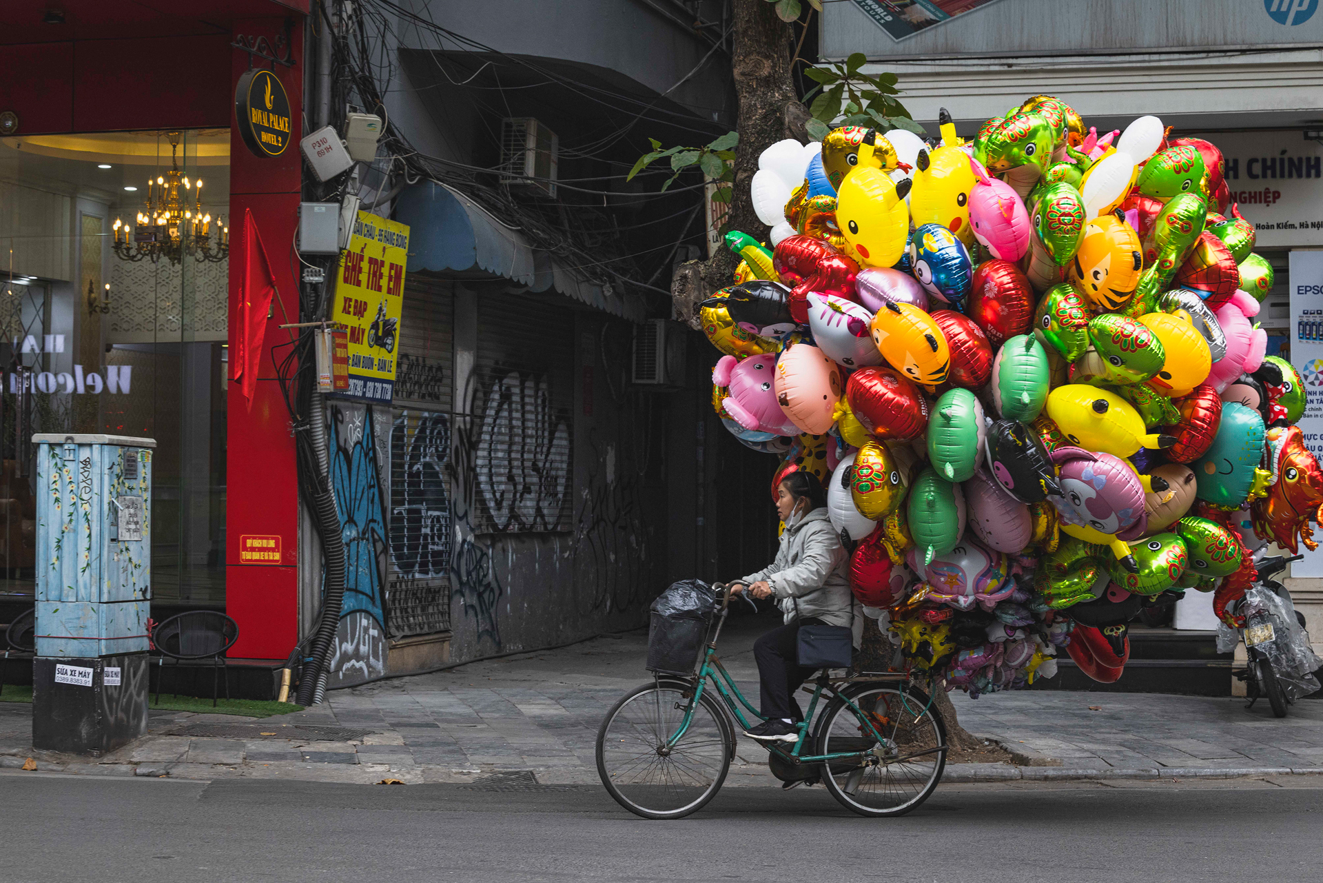 Vendedor de globos de colores montado en bicicleta en una calle de Vietnam