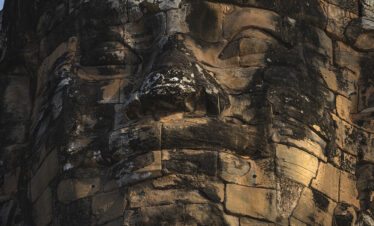 Rostro monumental tallado en piedra arenisca de un templo jemer en Camboya, con detalles erosionados por el tiempo