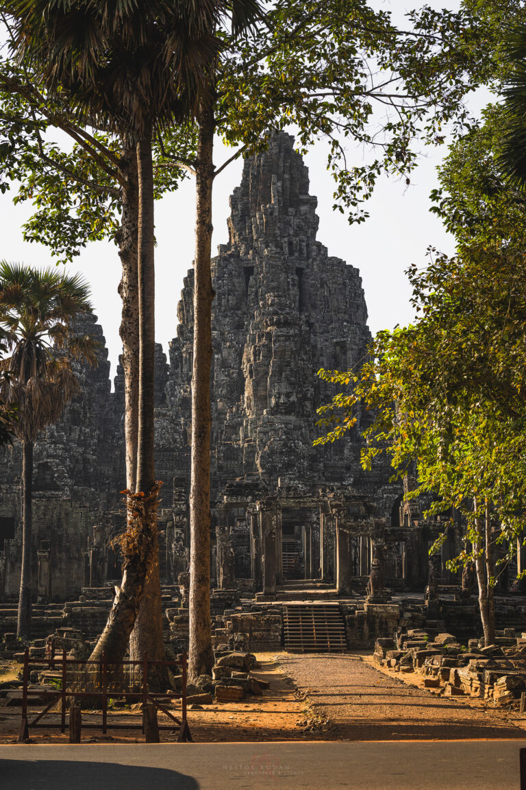 Templo antiguo de piedra en Camboya rodeado de árboles tropicales y palmeras, con torres de arquitectura jemer al fondo