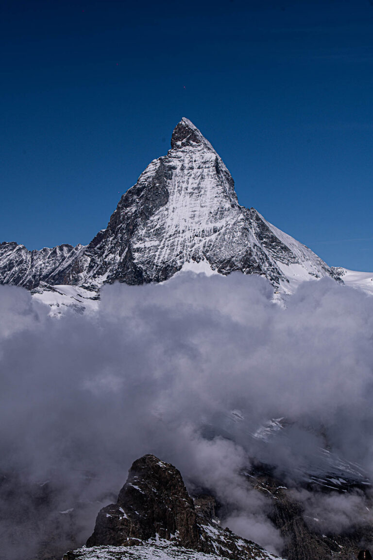 Pico nevado del Matterhorn emergiendo sobre un mar de nubes bajo cielo azul despejado