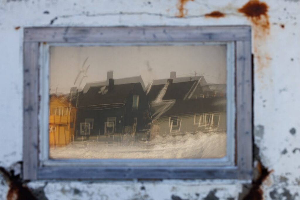 Casas tradicionales nórdicas nevadas fotografiadas a través de marco vintage desgastado