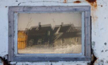 Casas tradicionales nórdicas nevadas fotografiadas a través de marco vintage desgastado
