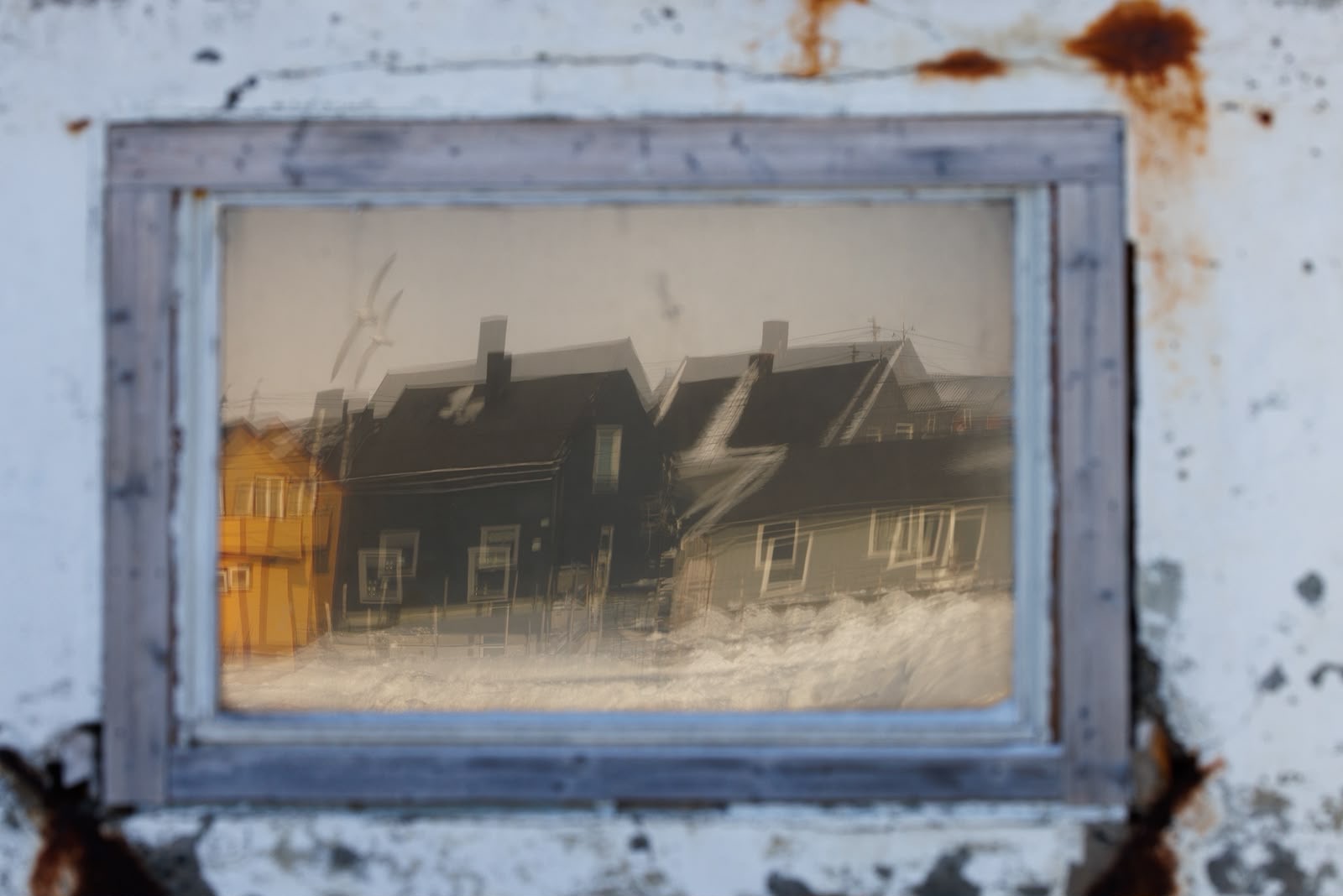 Casas tradicionales nórdicas nevadas fotografiadas a través de marco vintage desgastado