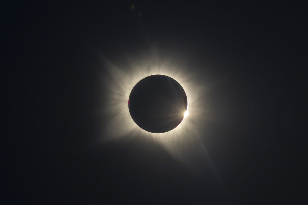 Eclipse solar total con corona visible alrededor de la luna negra contra cielo oscuro