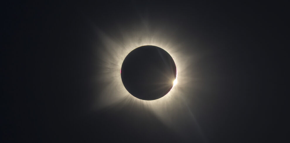 Eclipse solar total con corona visible alrededor de la luna negra contra cielo oscuro