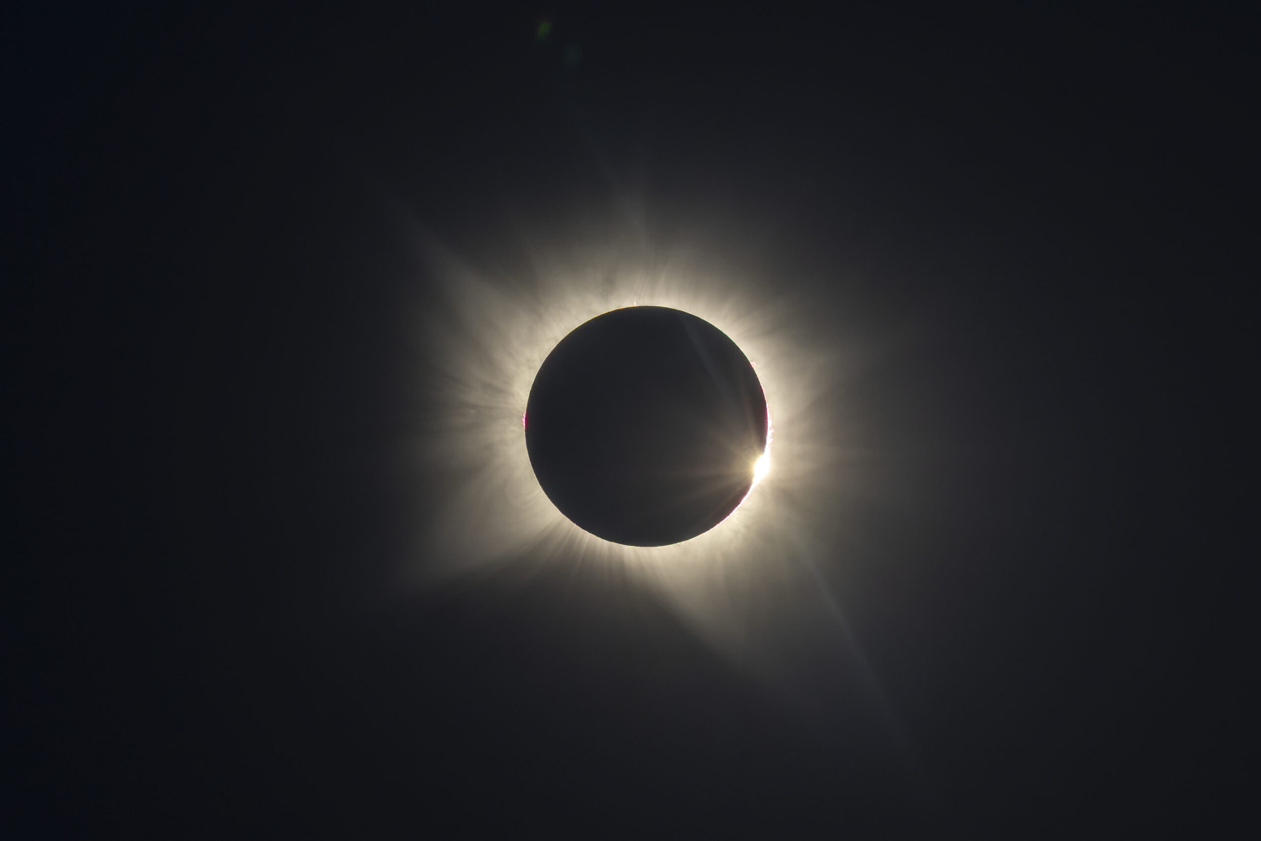 Eclipse solar total con corona visible alrededor de la luna negra contra cielo oscuro