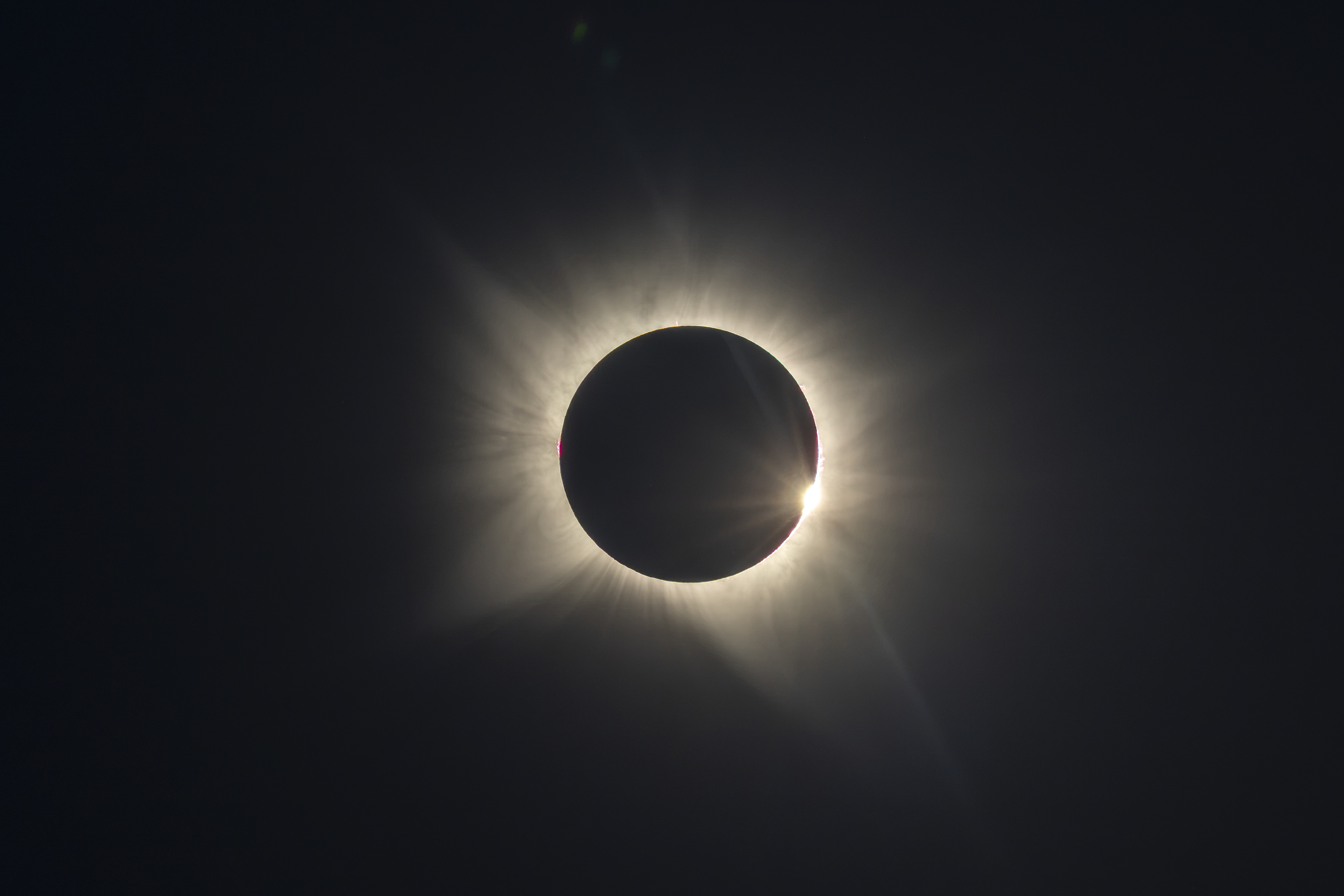 Eclipse solar total con corona visible alrededor de la luna negra contra cielo oscuro