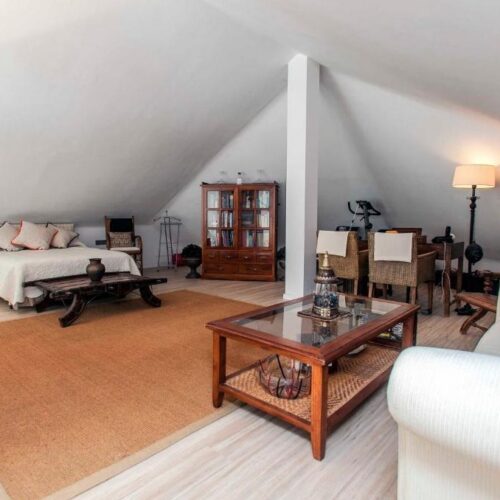 Lujoso ático abuhardillado con dos camas, zona de estar con chimenea, muebles de madera y decoración cálida en tonos beige