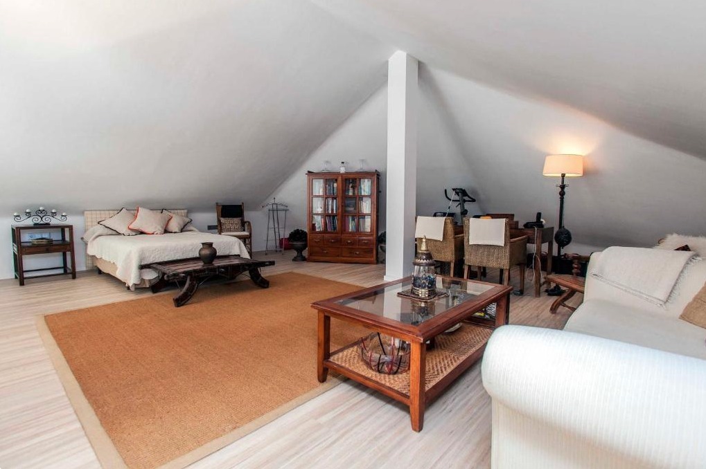 Lujoso ático abuhardillado con dos camas, zona de estar con chimenea, muebles de madera y decoración cálida en tonos beige