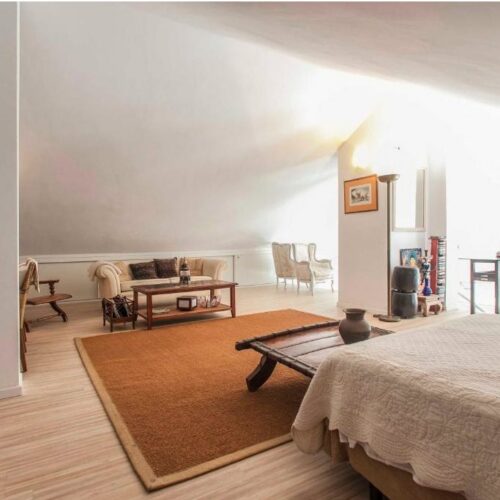 Dormitorio principal en villa de lujo con cama, zona de estar y vista a sala contigua con chimenea