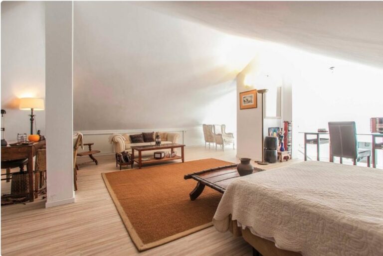 Dormitorio principal en villa de lujo con cama, zona de estar y vista a sala contigua con chimenea