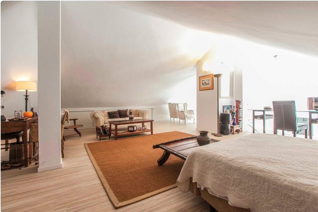 Dormitorio principal en villa de lujo con cama, zona de estar y vista a sala contigua con chimenea