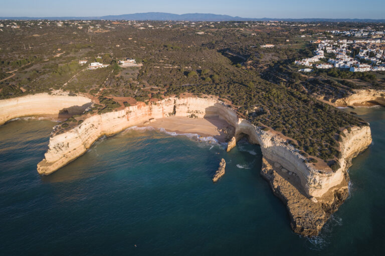 Acantilados de piedra caliza blanca con playa y formaciones rocosas en el Algarve portugués