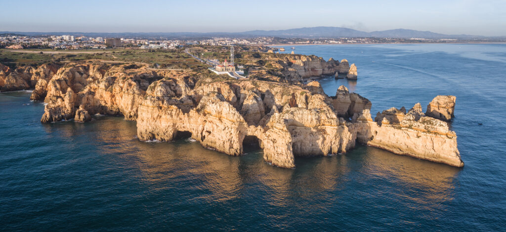 Acantilados de piedra dorada con cuevas marinas en la costa del Algarve, Portugal, junto a aguas azul turquesa