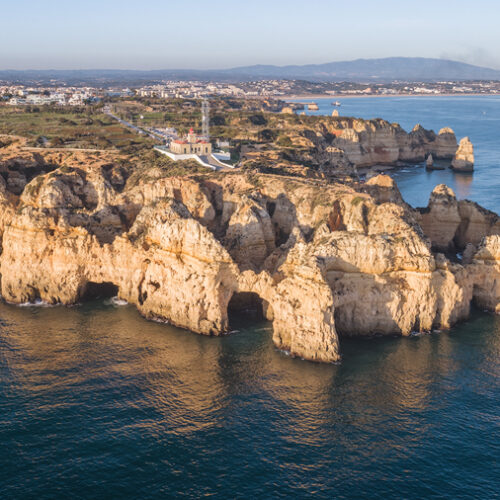 Acantilados de piedra dorada con cuevas marinas en la costa del Algarve, Portugal, junto a aguas azul turquesa